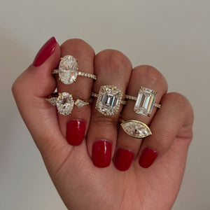 model holding several bold engagement rings with center weights above 4 carats