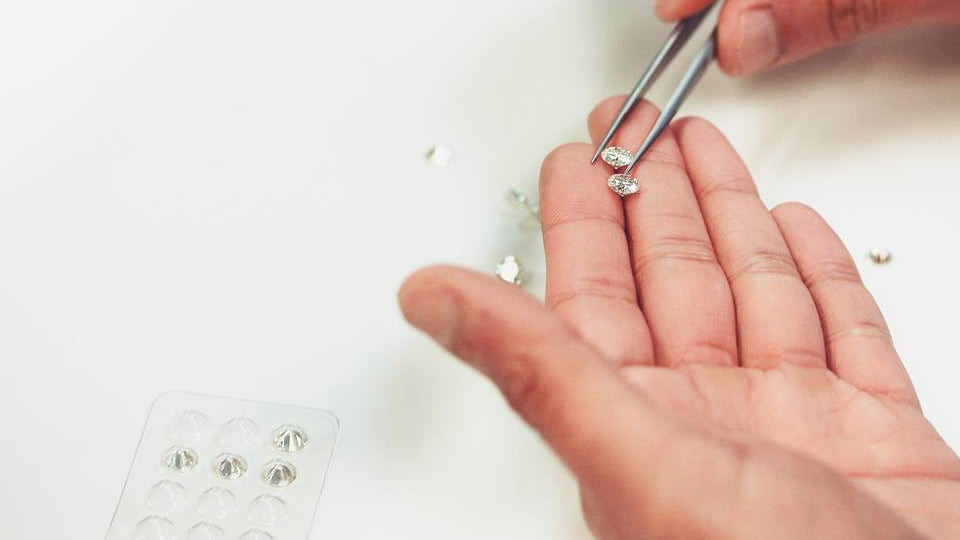 person selecting faceted moissanite gemstones