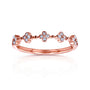 A rose gold band ring featuring a row of small four-petal flower motifs set with clear round diamonds