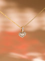 A Kobelli heart-shaped diamond pendant on a gold chain against a blurred warm background