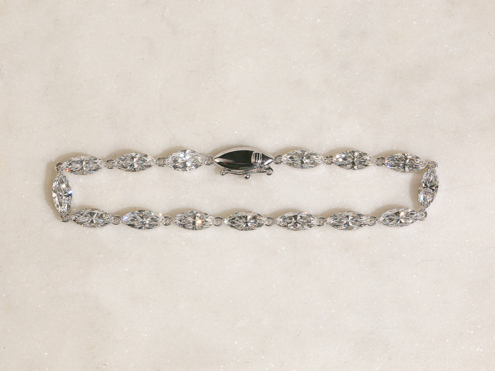 lab-grown diamond bracelet in white gold - top angle of bracelet on off-white table