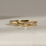 Yellow gold ring with a twisted band design, featuring rows of gold, one lined with diamonds.