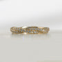 Yellow gold band featuring two twisted rows of small pavé diamonds, photographed on a clean white semi-reflective surface.
