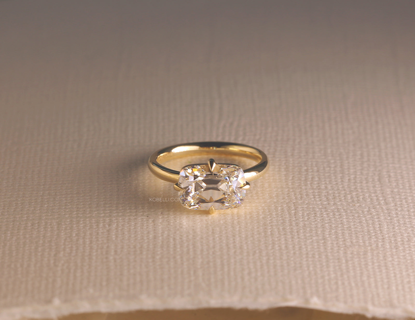lifestyle image of old mine-cut diamond ring laid flat on an off-white thick woven cardstock sheet