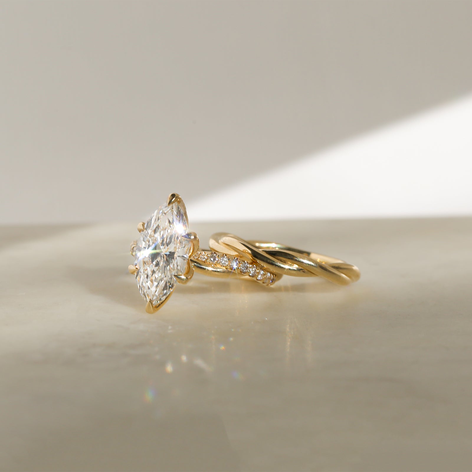 3.25 Carat Lab Grown Diamond Marquise Shifting Helix Ring paired to the Plain Helix Wedding Band Ring - side angle resting on a white table
