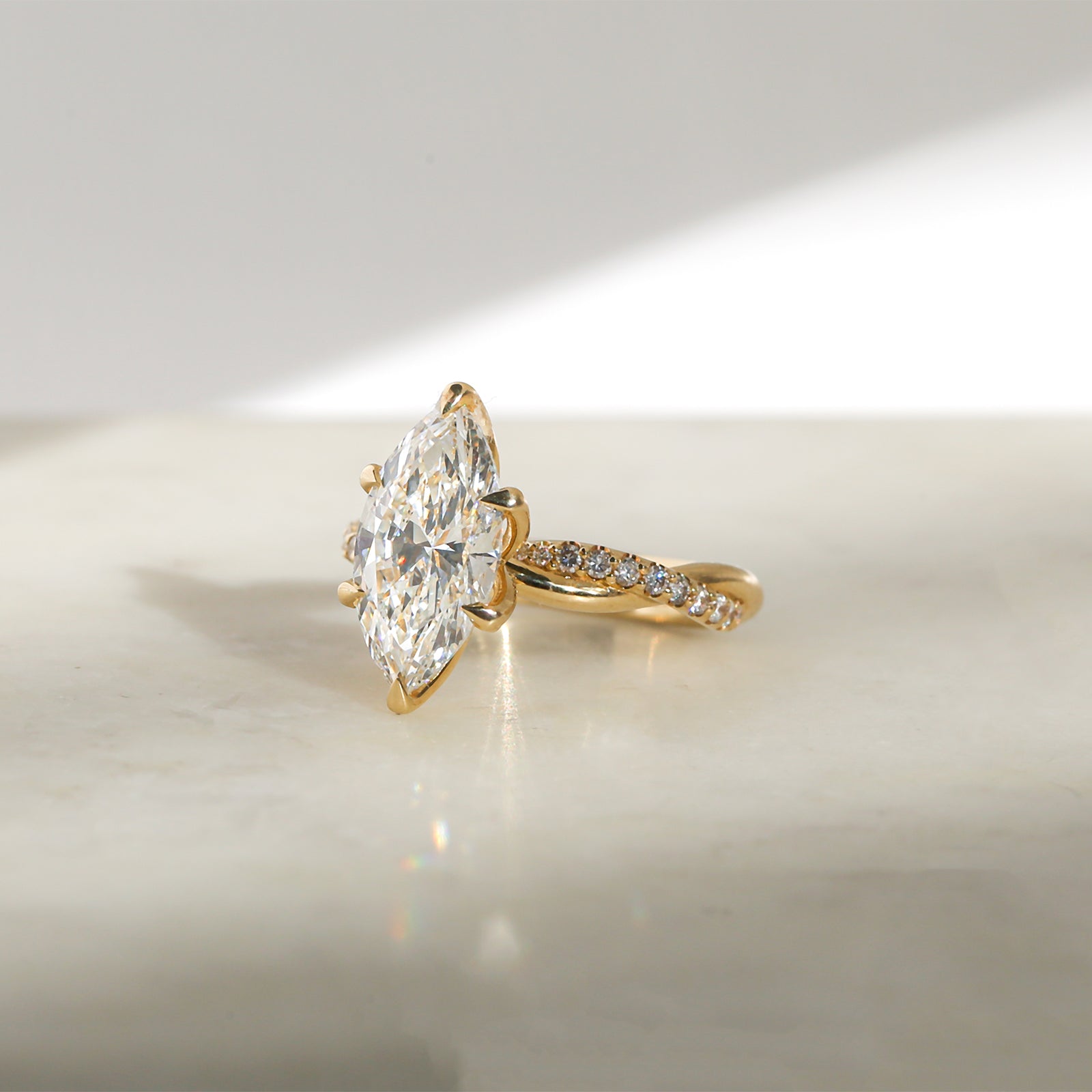 3.25 Carat Lab Grown Diamond Marquise Shifting Helix Ring - side angle resting on a marbled white table