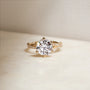 3.25 Carat Lab Grown Diamond Round Shifting Helix Ring - lifestyle image of yellow gold option resting on an off-white table with subdued daylight