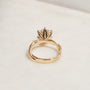 3.25 Carat Lab Grown Diamond Round Shifting Helix Ring - lifestyle image of yellow gold option resting on an off-white table with subdued daylight, photographed at a back angle of the ring