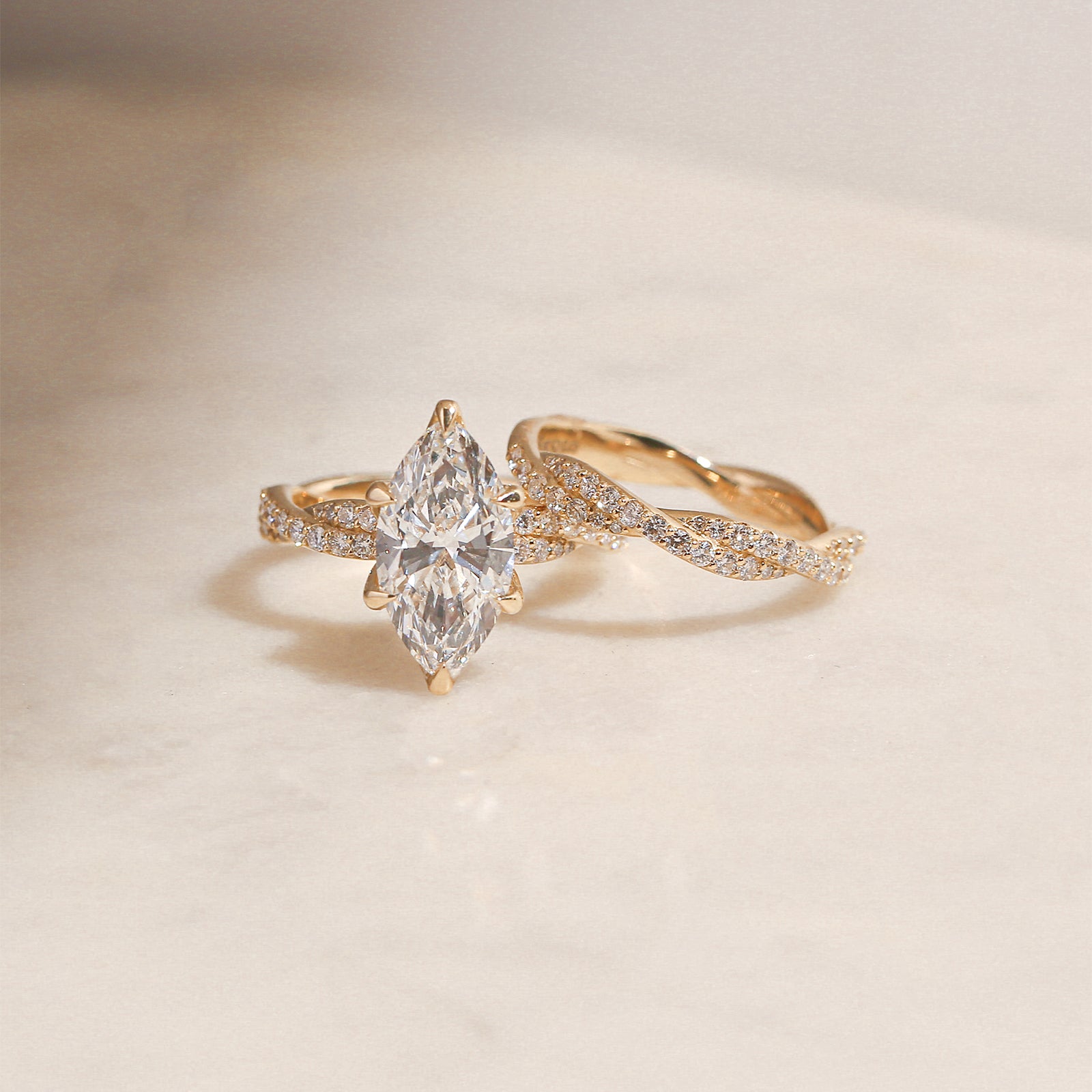 3.5 Carat Lab Grown Diamond Marquise Double Helix Ring Solid 14k Yellow Gold gently stacked with the Diamond Double Helix Wedding Band - lifestyle image resting on a white surface