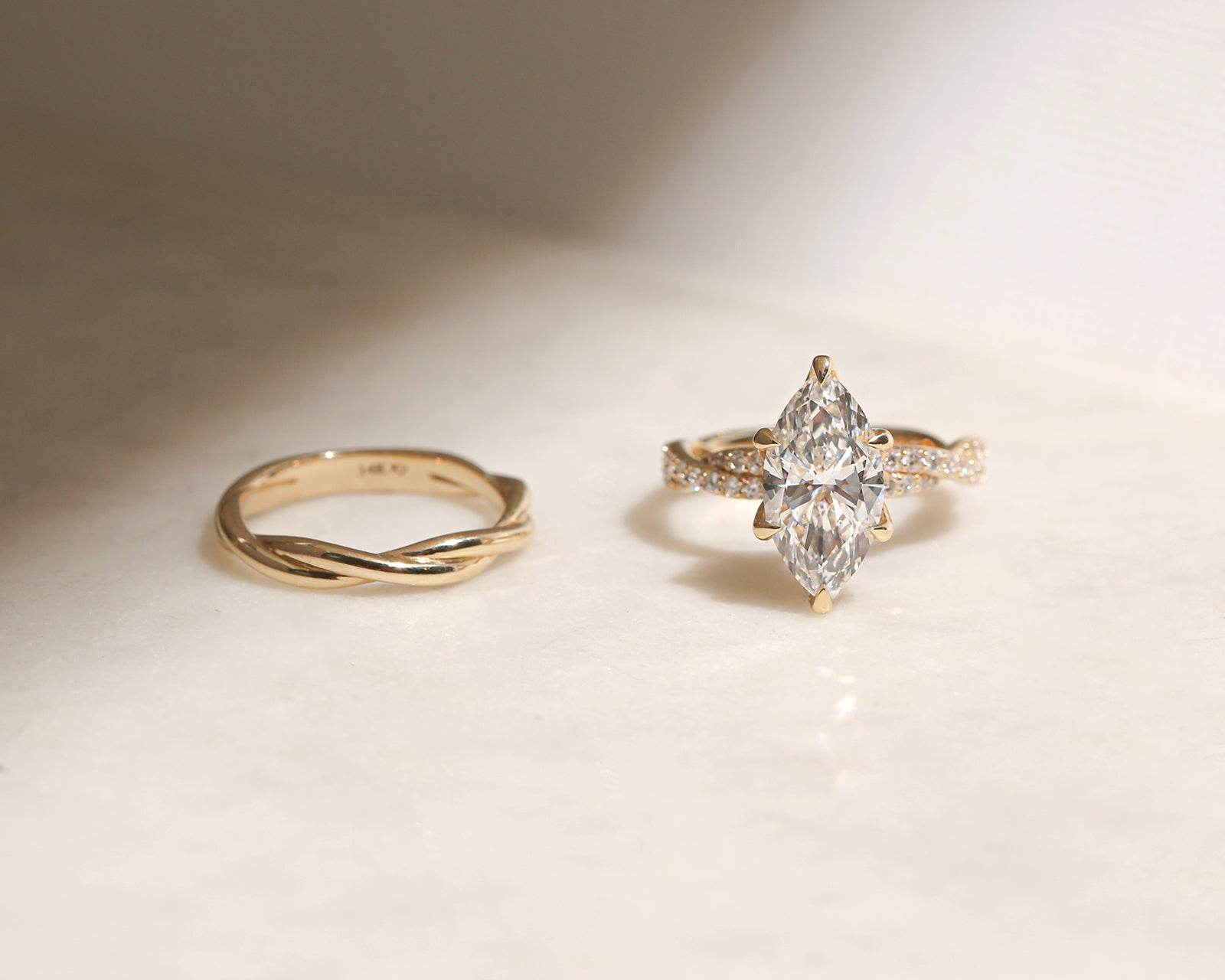 3.5 Carat Lab Grown Diamond Marquise Double Helix Ring Solid 14k Yellow Gold paired to the Plain Gold Helix Wedding Band - lifestyle image resting on a table in indirect sunlight