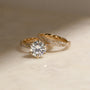 lifestyle image of the Round Diamond Double Helix Engagement Ring with the Diamond Double Helix Wedding Band leaning on one side of it
