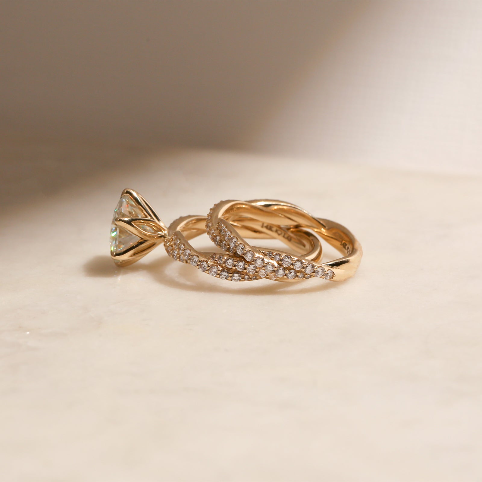 lifestyle image of the Round Diamond Double Helix Engagement Ring with the Diamond Double Helix Wedding Band leaning on one side of it, shot at a full size angle
