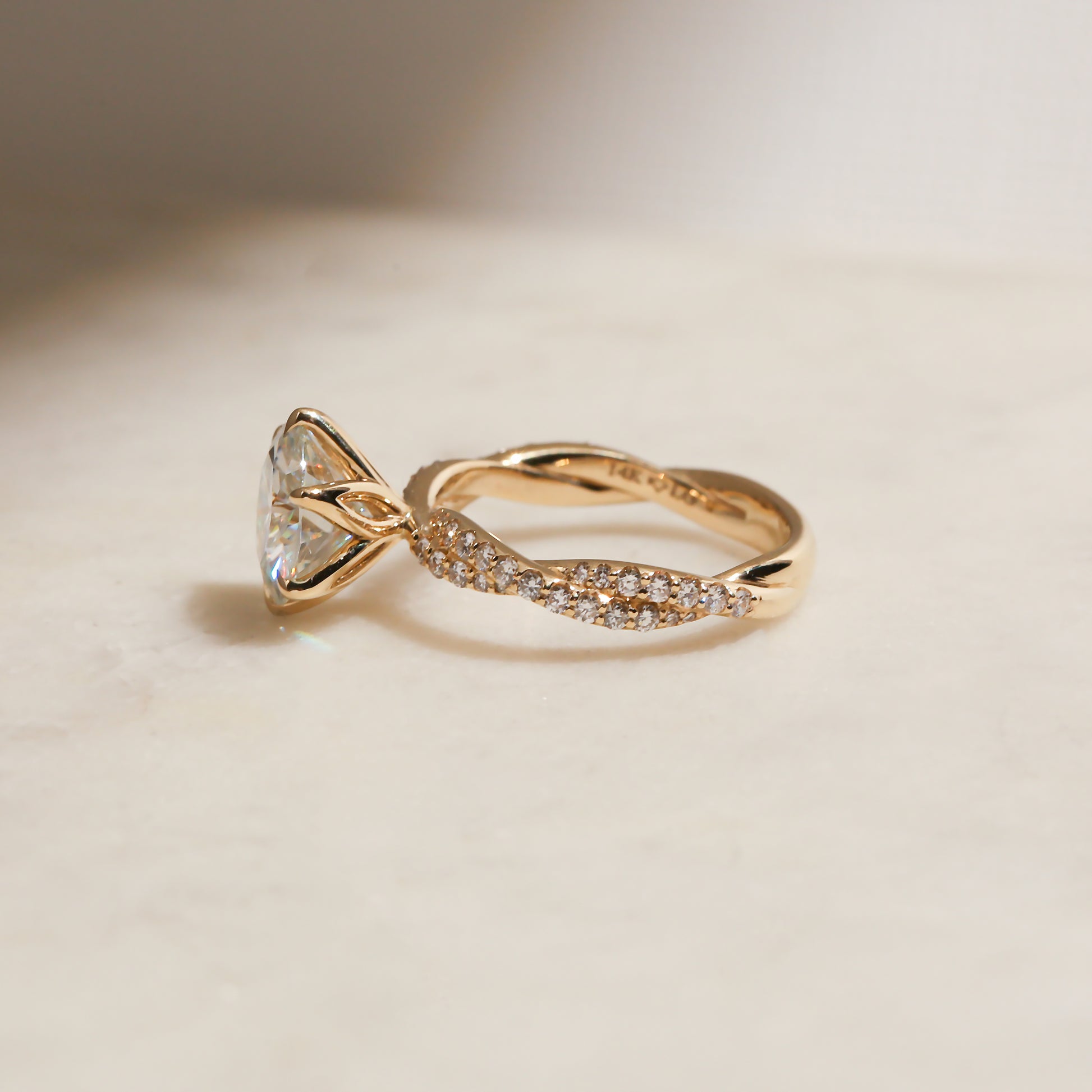 lifestyle image of the Double Helix Round Diamond Ring resting on a white table, shot at a full side angle