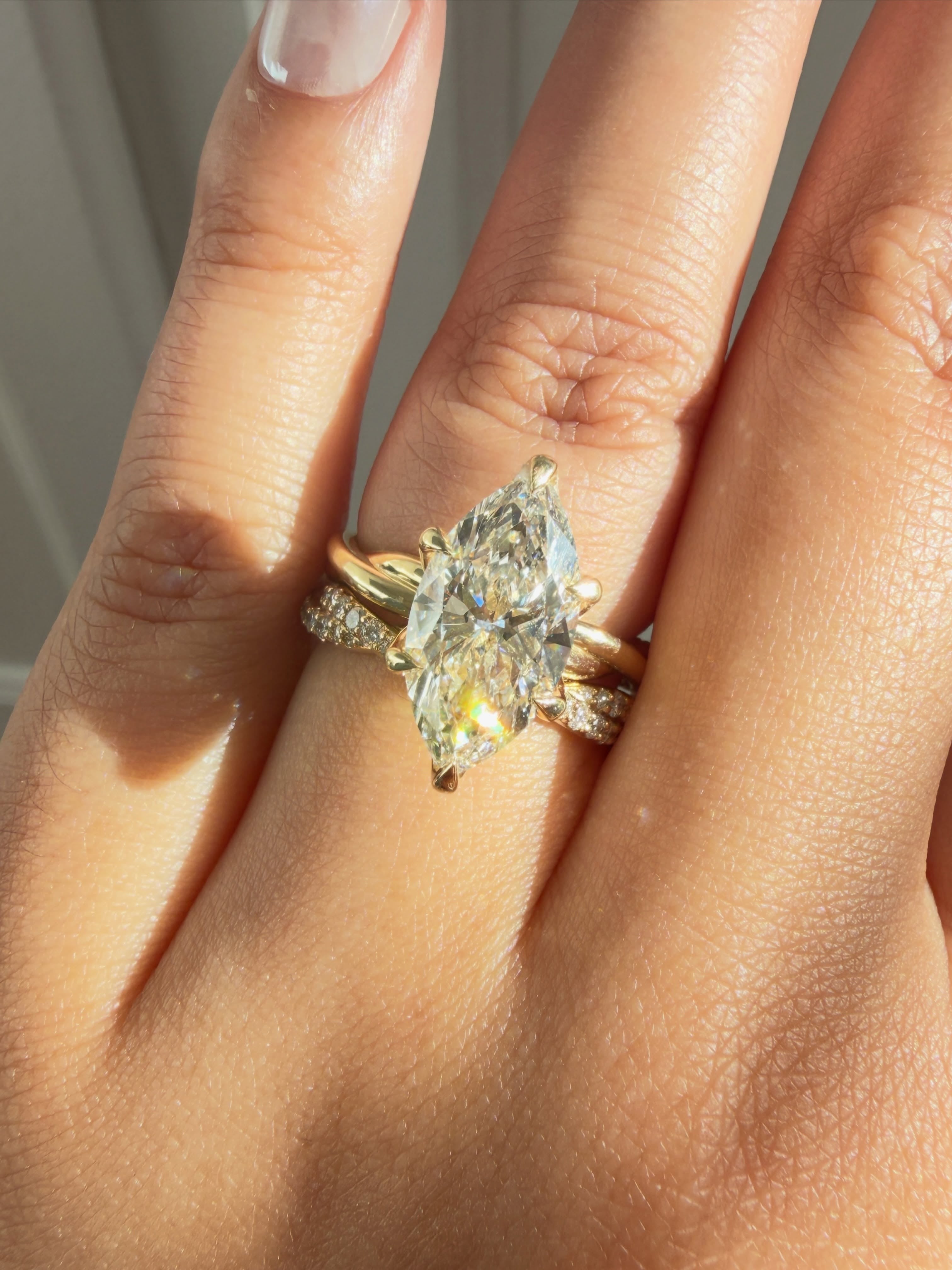 Close-up of the Kobelli Marquise Helix Ring paired to the Double Helix Wedding Band - lab grown diamonds, solid 14k yellow gold, worn on a hand
