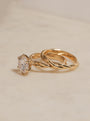 Yellow gold solitaire ring with a round diamond center and a twisted gold band, displayed on a light beige marble surface.