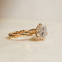 Yellow gold Kobelli Helix Ring with a twisted plain band and a large round-cut diamond in a prong setting, photographed on a light neutral tone surface.