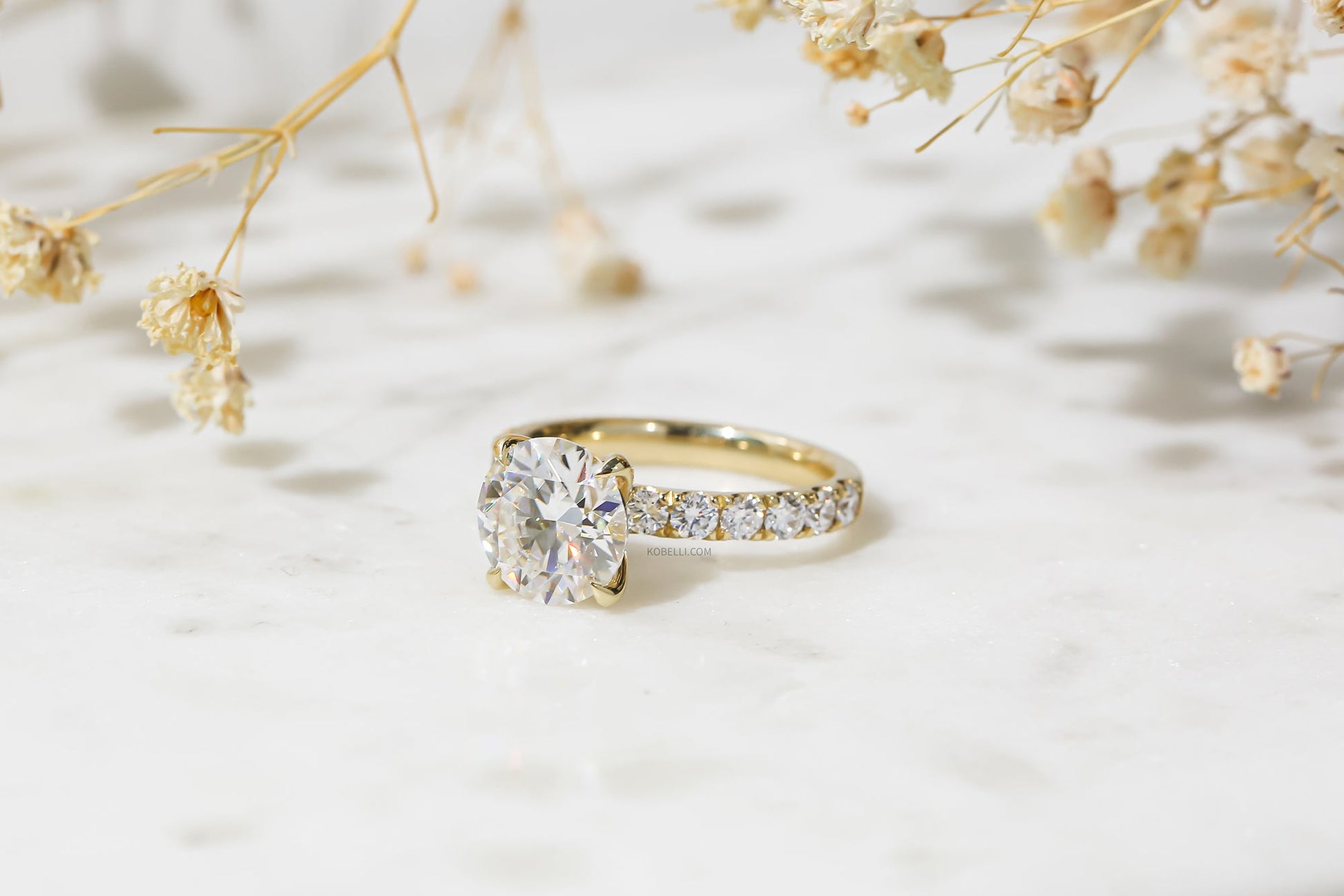 Kobelli Grown Diamond Ring 3ct Round in Yellow Gold - at an angle with floral backdrop
