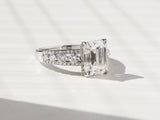Anel de noivado de moissanite esmeralda Kobelli e diamantes redondos de fileira tripla