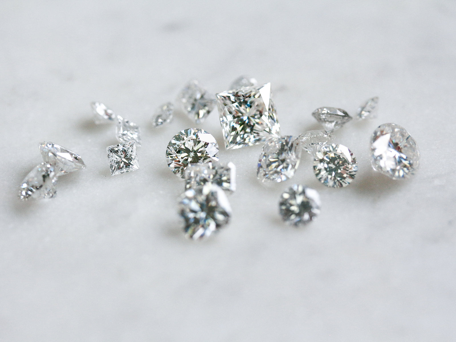 loose princess, round, and cushion diamonds on white table