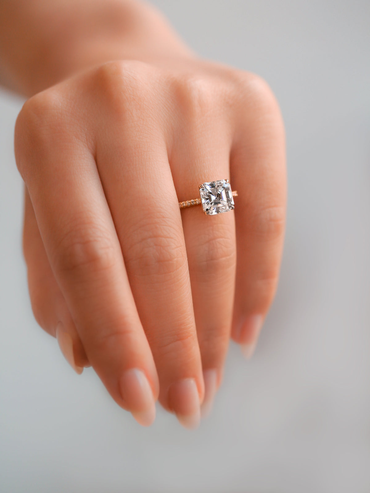 Asscher-cut engagement ring from the Petite Collection on a hand - slender bands with contrasting large centers