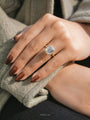 Emerald-cut halo engagement ring on a hand